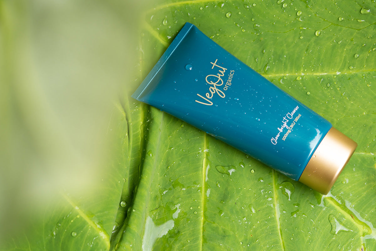 Veg Out Organics vegan skincare tube resting on a vibrant green leaf with water droplets, symbolizing plant-based, eco-friendly, and cruelty-free beauty.