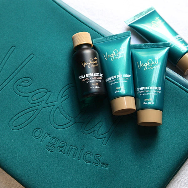 Travel-size vegan skincare kit by Veg Out Organics with body oil, lotion, and exfoliator on branded bag